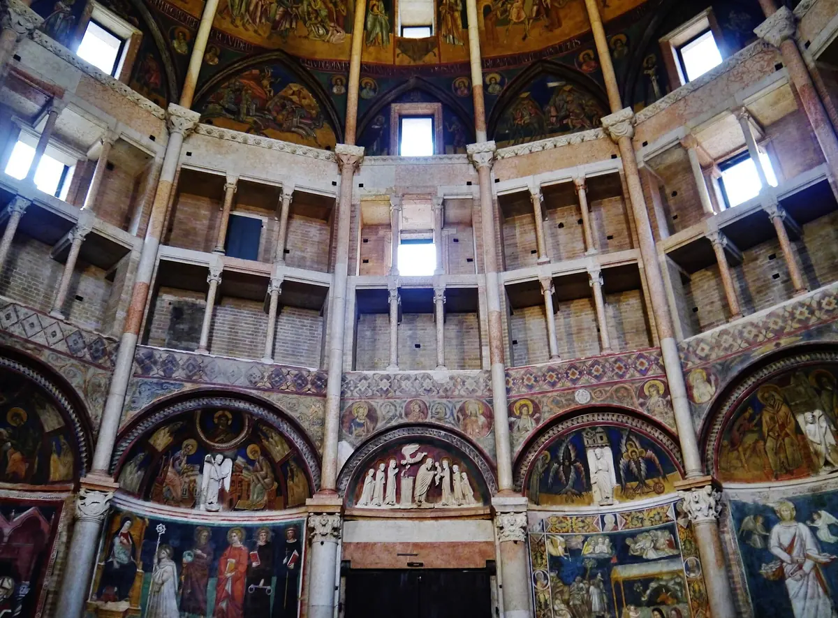 Innenraum des Baptisteriums von Parma mit freskierten Lünetten, gestaffelten Galerien und der bemalten Kuppel