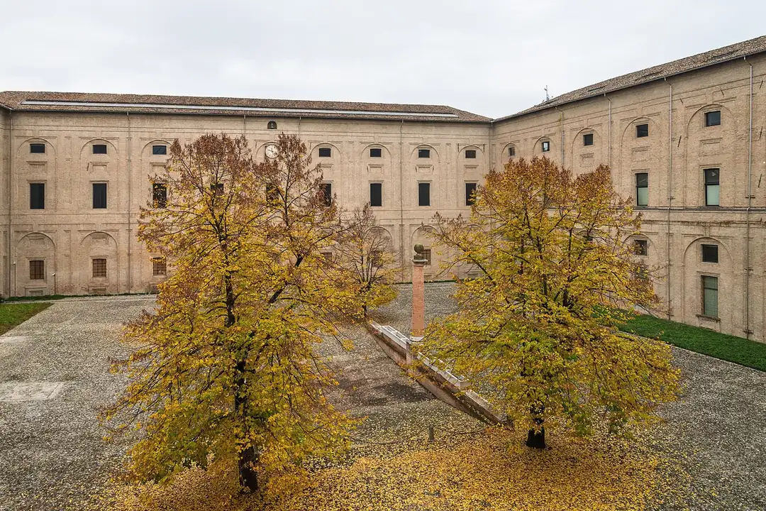 Innenhof des Palazzo della Pilotta mit zwei Herbstbäumen zwischen seinen Backsteinflügeln