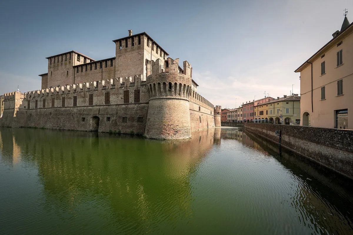 Douves vertes de la Rocca Sanvitale avec la tour ronde du château et les arcades de Fontanellato