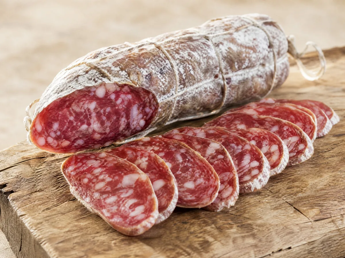 A Salame di Felino tied with string, partly sliced into long angled slices