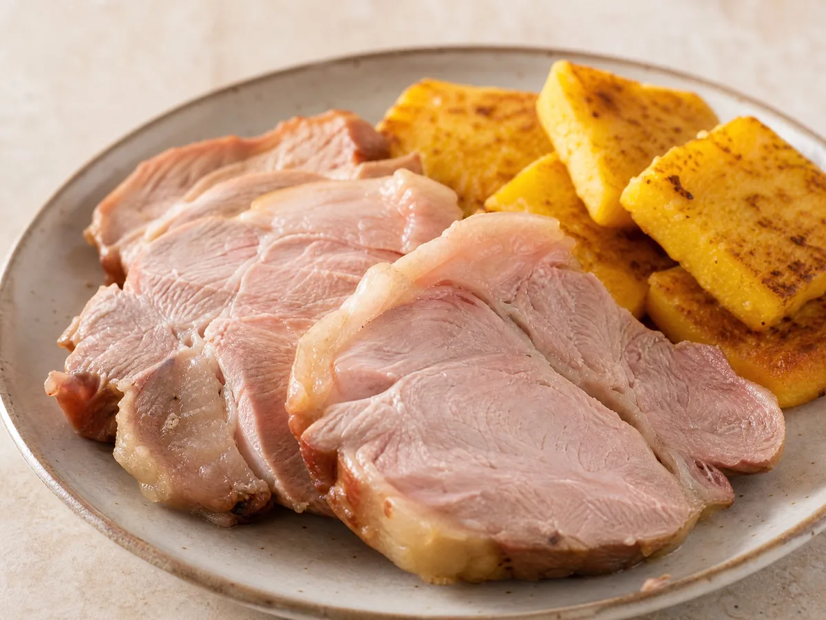 Warm slices of cooked pork shoulder with squares of fried polenta