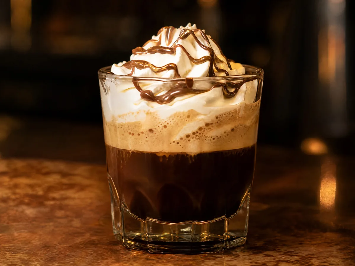 Espresso topped with whipped cream and a swirl of Nutella, served in a small glass