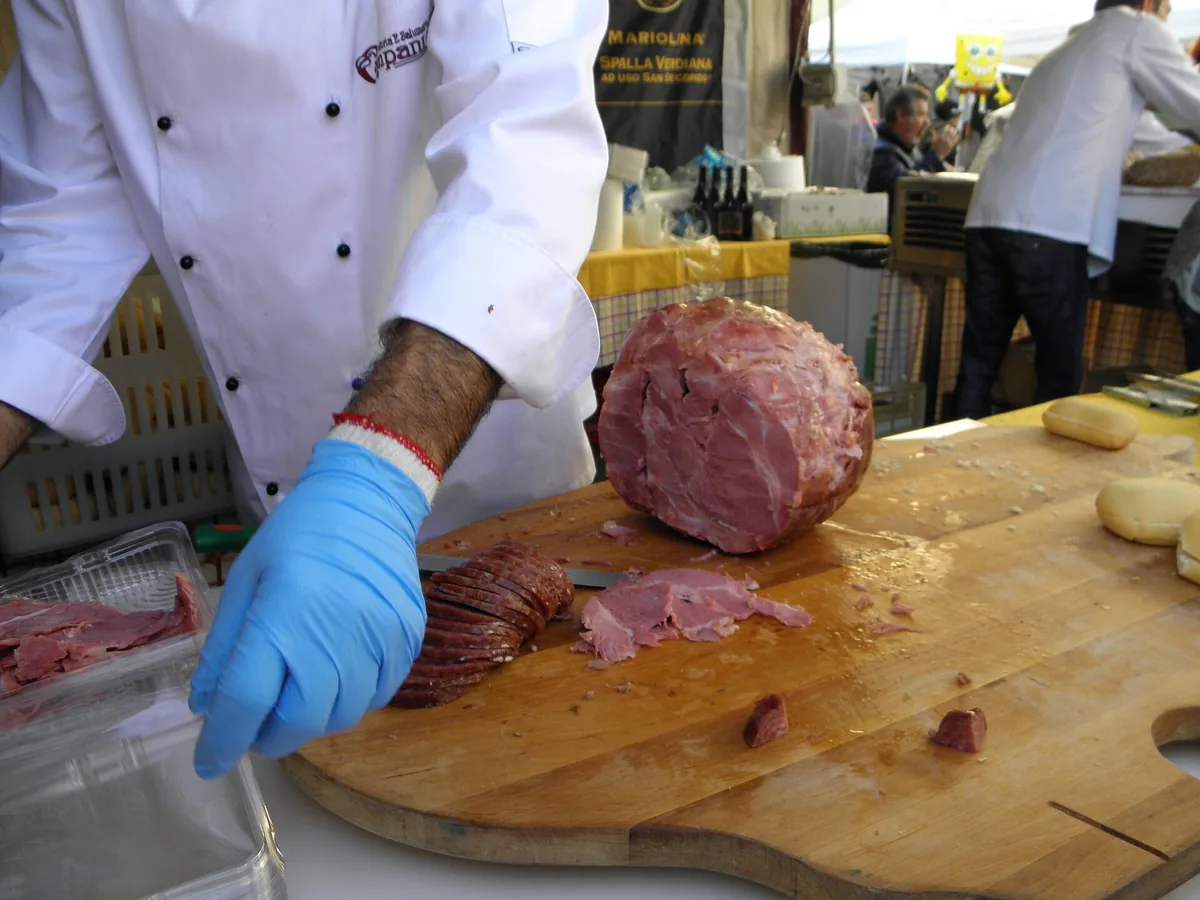 Koch, der warme spalla cotta auf einem Brett schneidet, auf dem Porc-Fest im November in Sissa