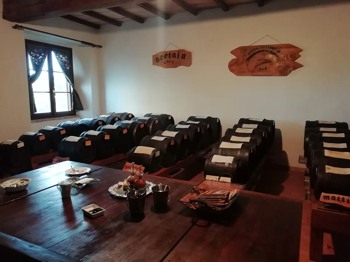 Reihen kleiner Balsamico-Essig-Fässer hinter einem Verkostungstisch in einer Acetaia in Modena