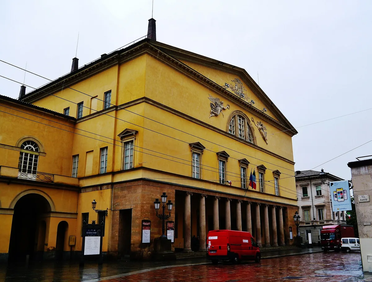 Yellow facade and portico of the Teatro Regio di Parma on a rainy day