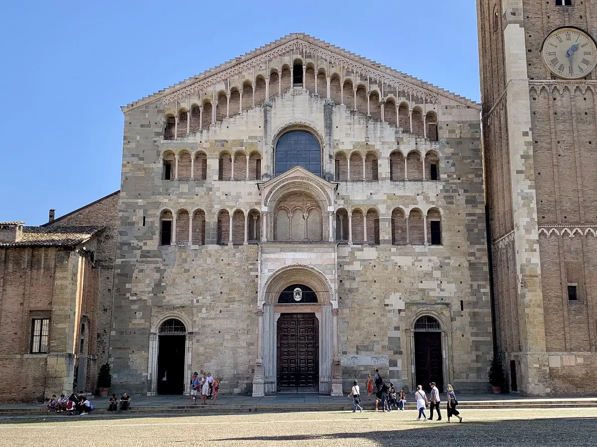 Romanische Fassade des Doms von Parma mit Loggien und Ziegelglockenturm unter blauem Himmel