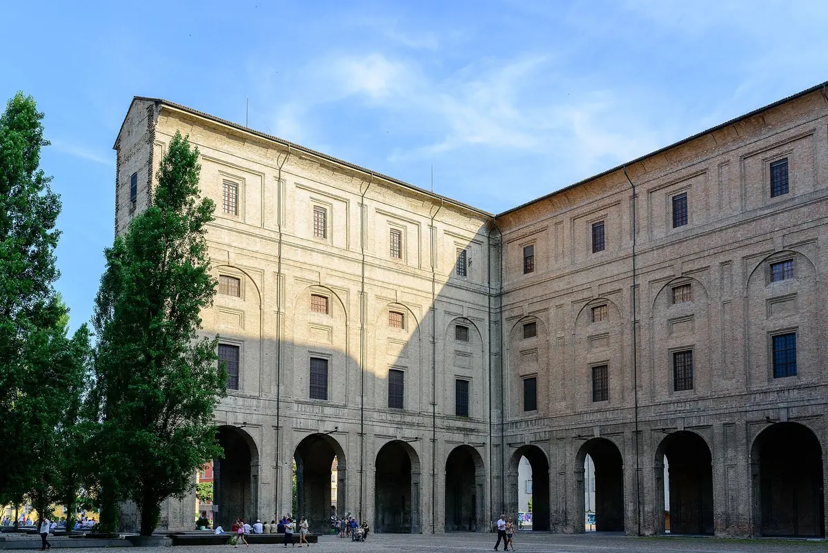 Ziegelsteintrakte und erdgeschossige Arkaden des Palazzo della Pilotta in Parma unter blauem Himmel