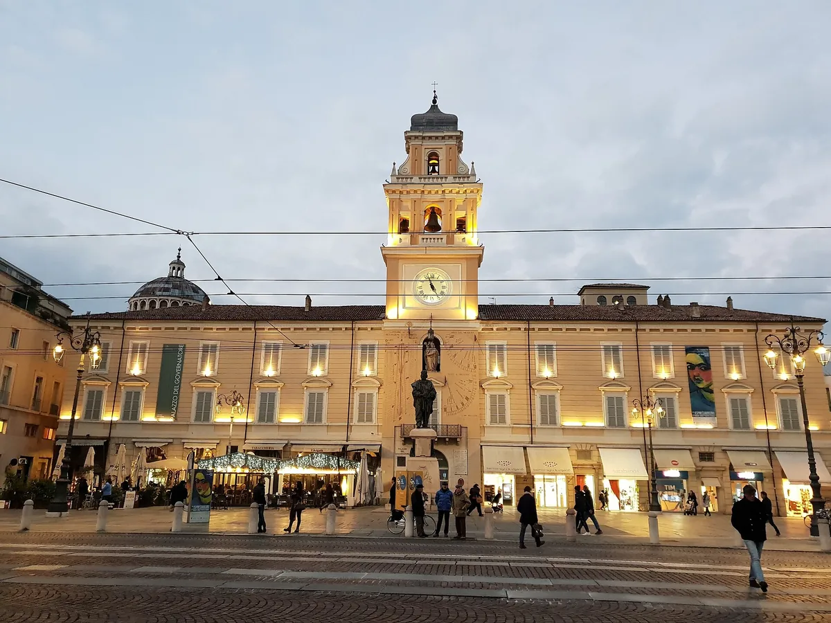 Palazzo del Governatore and its clock tower lit at dusk on Piazza Garibaldi, Parma