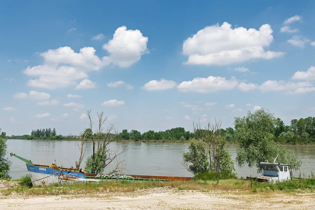 The broad Po river at Sissa Trecasali with fishing boats on the bank