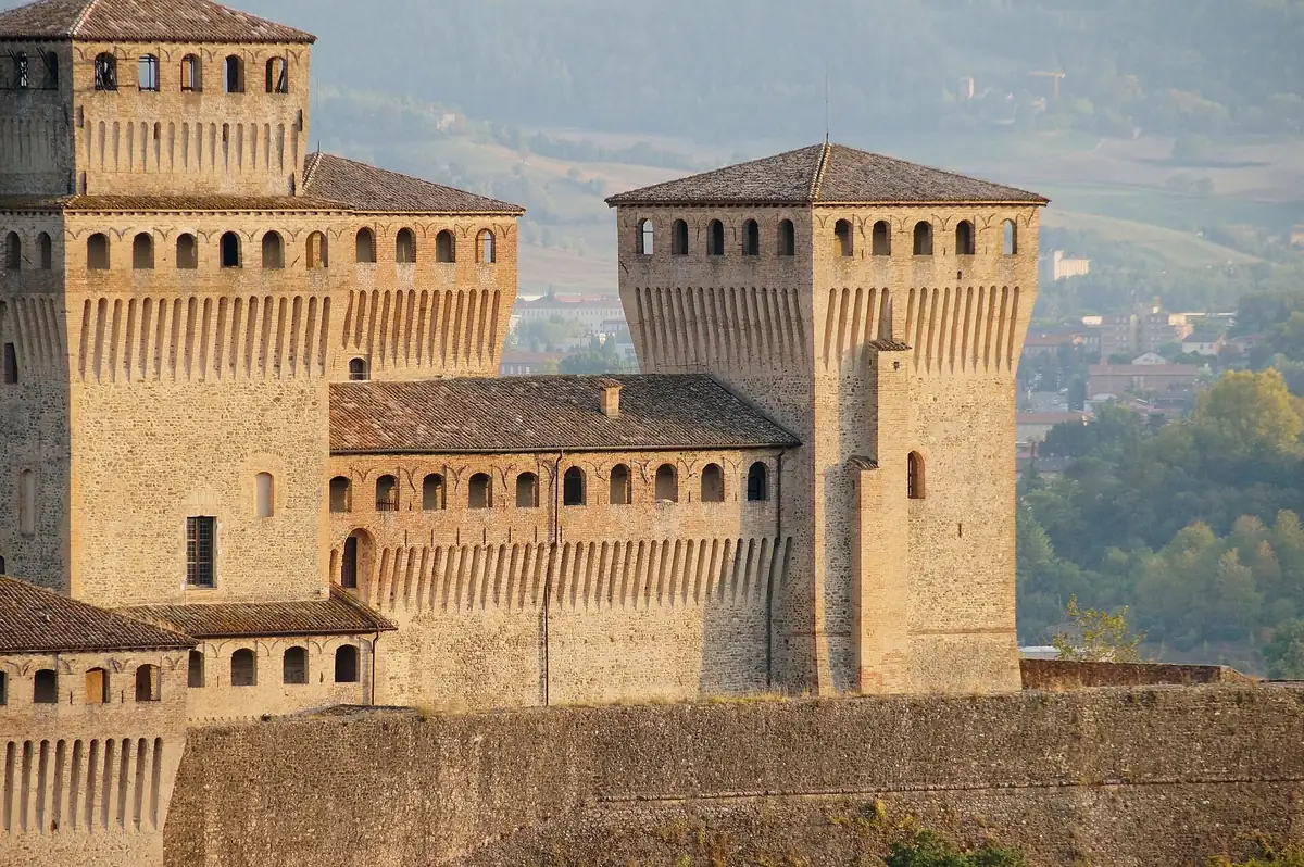 Quadratische Türme und Außenmauern der Burg Torrechiara vor grünen Hügeln