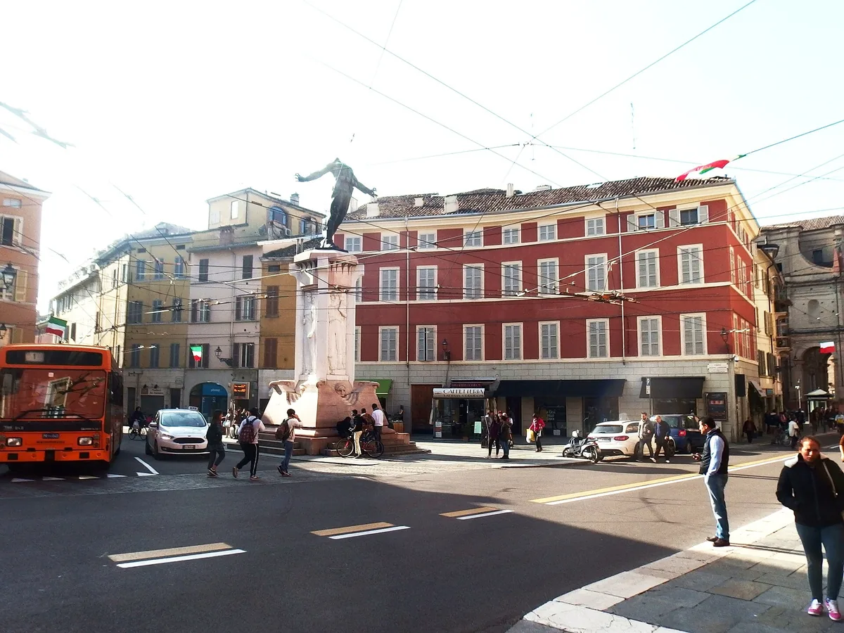 Piazza Corridoni in Parmas Oltretorrente mit der Corridoni-Statue und roten Gebäuden