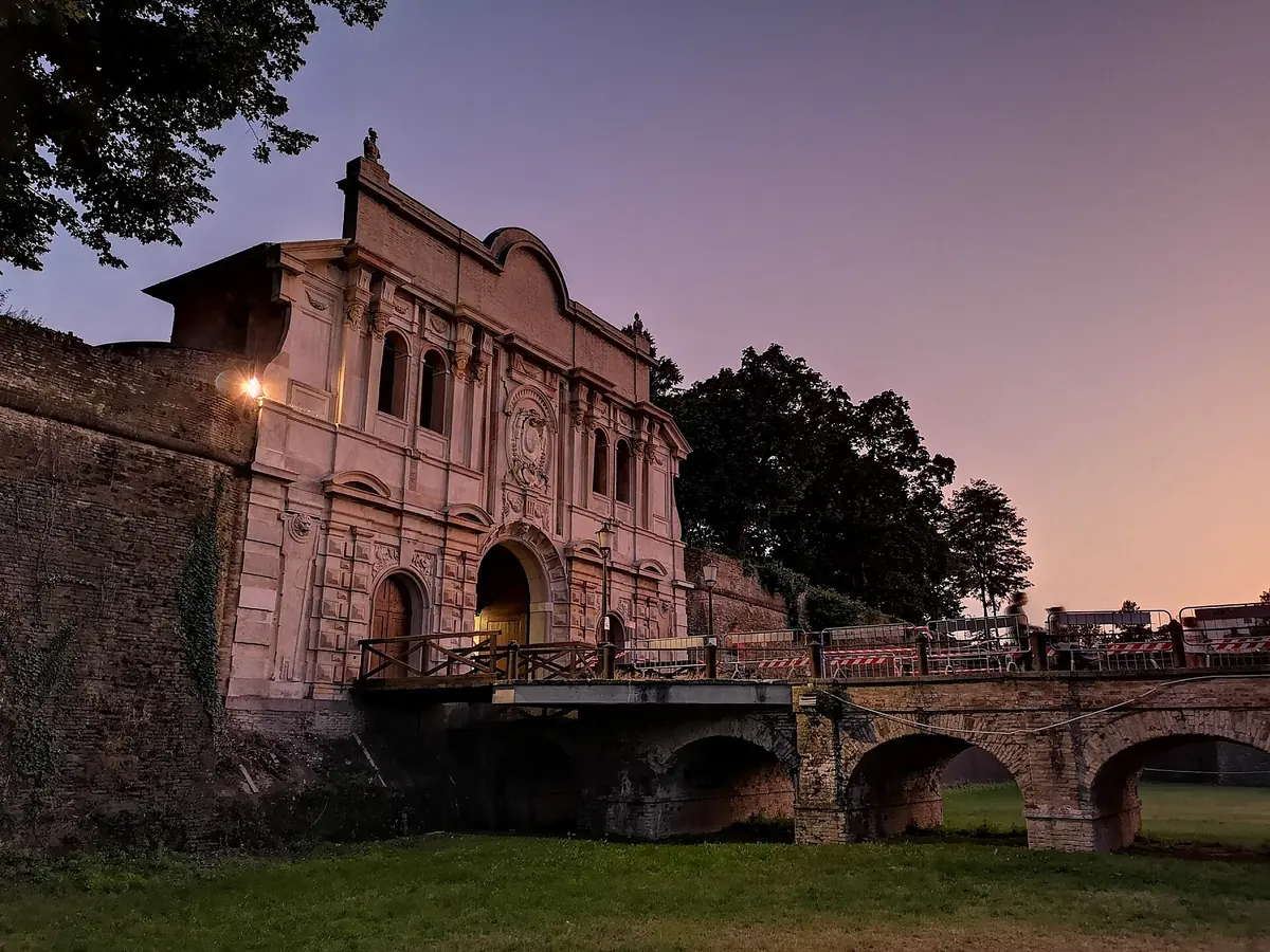 Monumental gate and brick bridge of Parma's Cittadella fortress at sunset