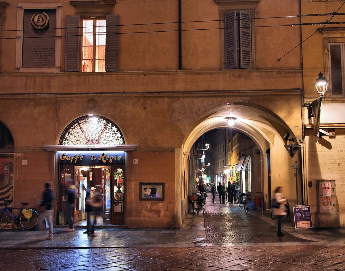 Café by the Teatro Regio lit up at night under an arcade in central Parma